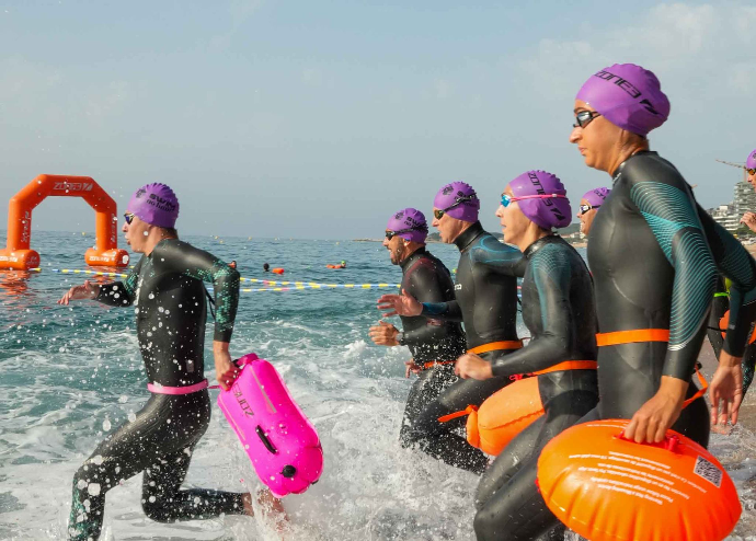 Participantes con gorras de colores nadando en aguas abiertas del Mediterráneo